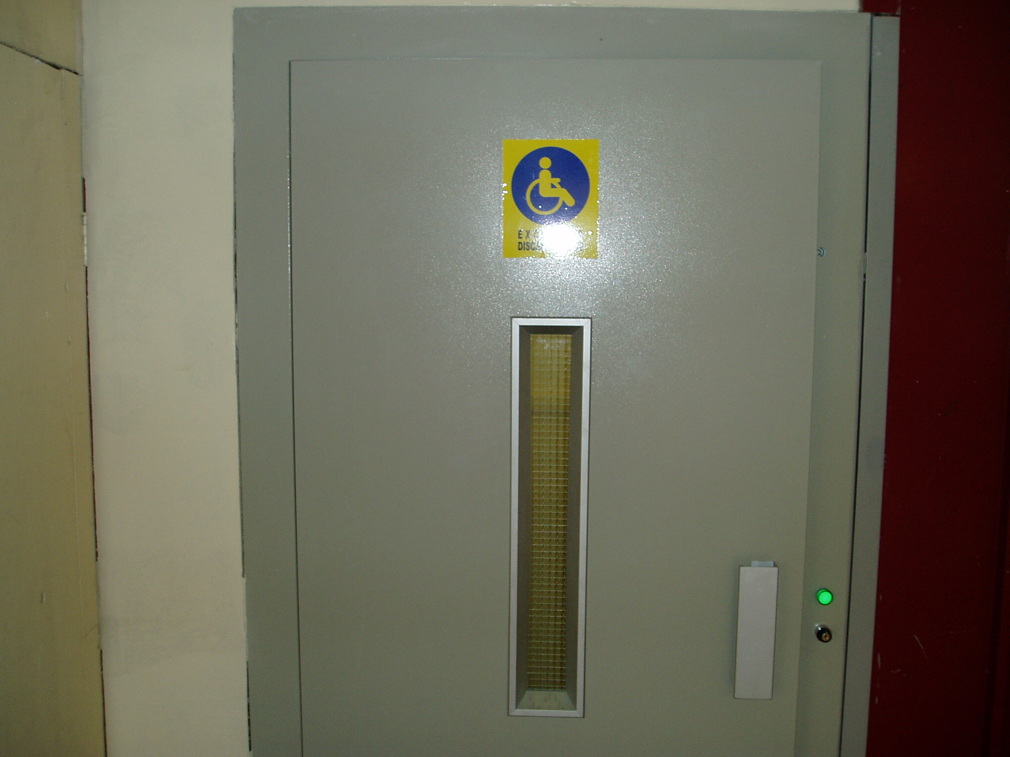 Cerradura electromecánica de puerta de piso con pestillo, brazo metálico y sistema de rodillos.