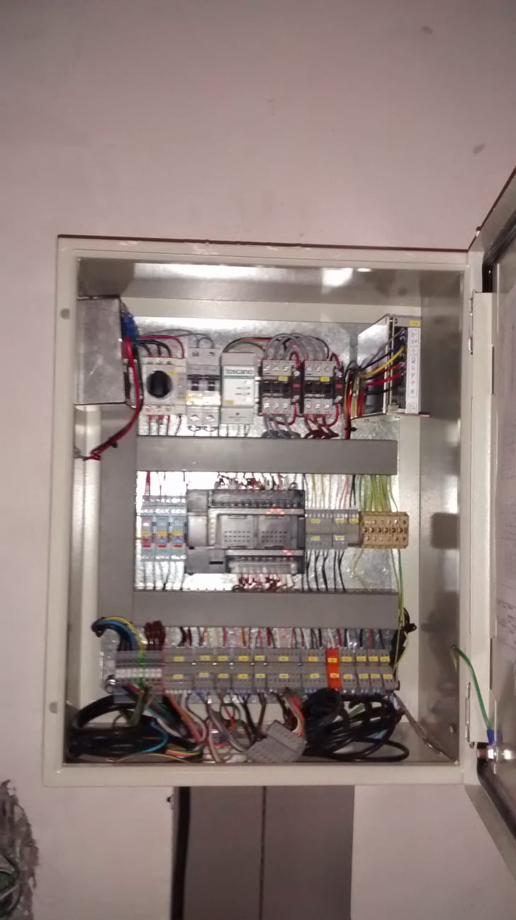 Tablero de potencia con PLC central, contactores Toscano, fuente de poder y conexiones etiquetadas.